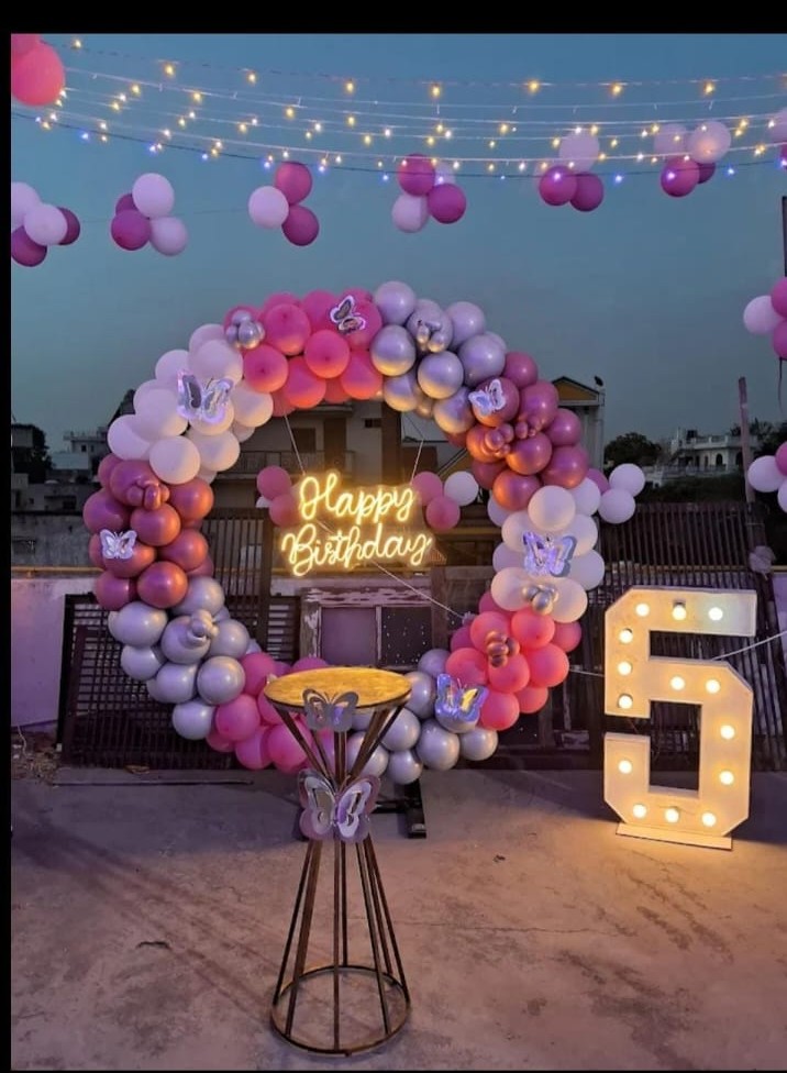 Pink, white and silver rooftop birthday balloon arch with illuminated number five